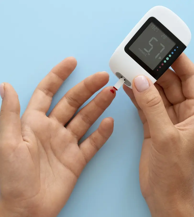 Person checking blood sugar levels with a glucometer on blue background.