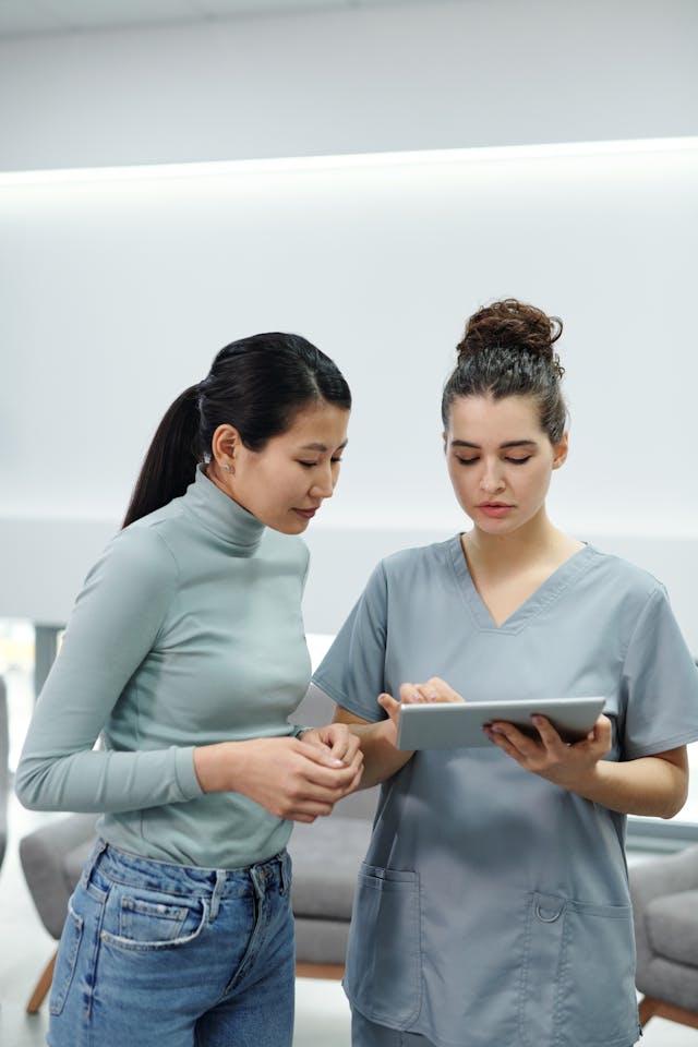 Healthcare professional consulting with a patient and reviewing information on a tablet in a modern medical office.